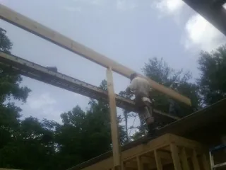 Carpenter setting a ridge beam over a new addition frame — Ice Dam Removal by Roofing Brothers in Colo
