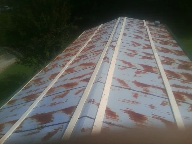 Rusted metal roof panels with new wood purlins before replacement — Storm Damage Roof Repair in Colo by Roofing Brothers
