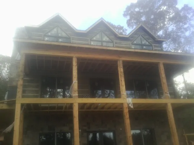Dormers and porch framing on a large log home under construction — Roof Coating work by our crew in Colo