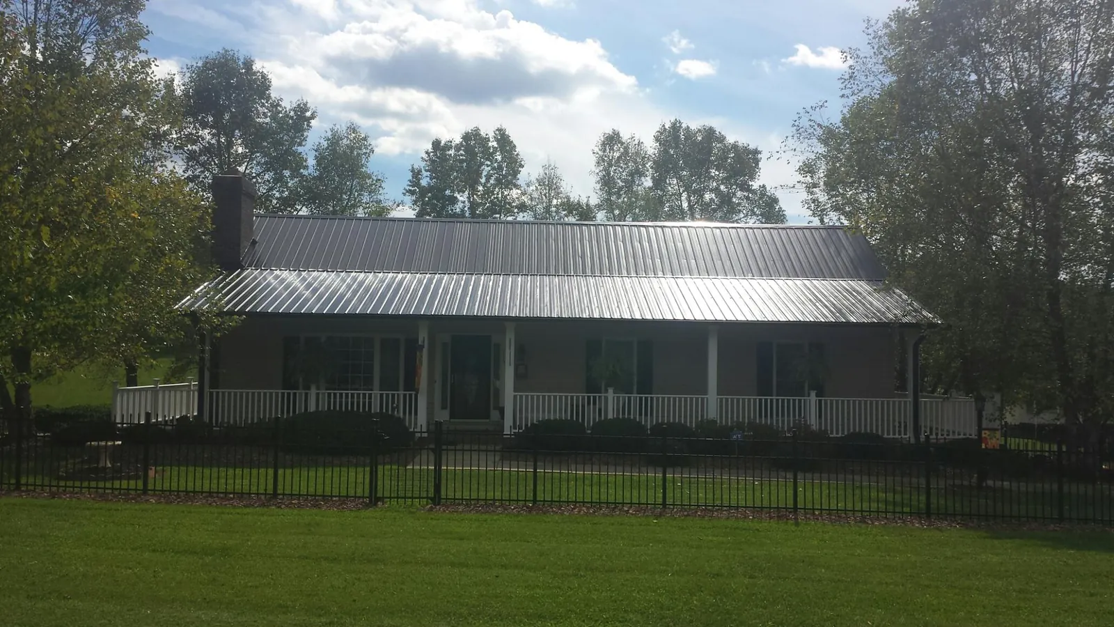 Gray metal roof on a brick ranch with a full width front porch — Gutter Guard Installation work by our crew in Colo