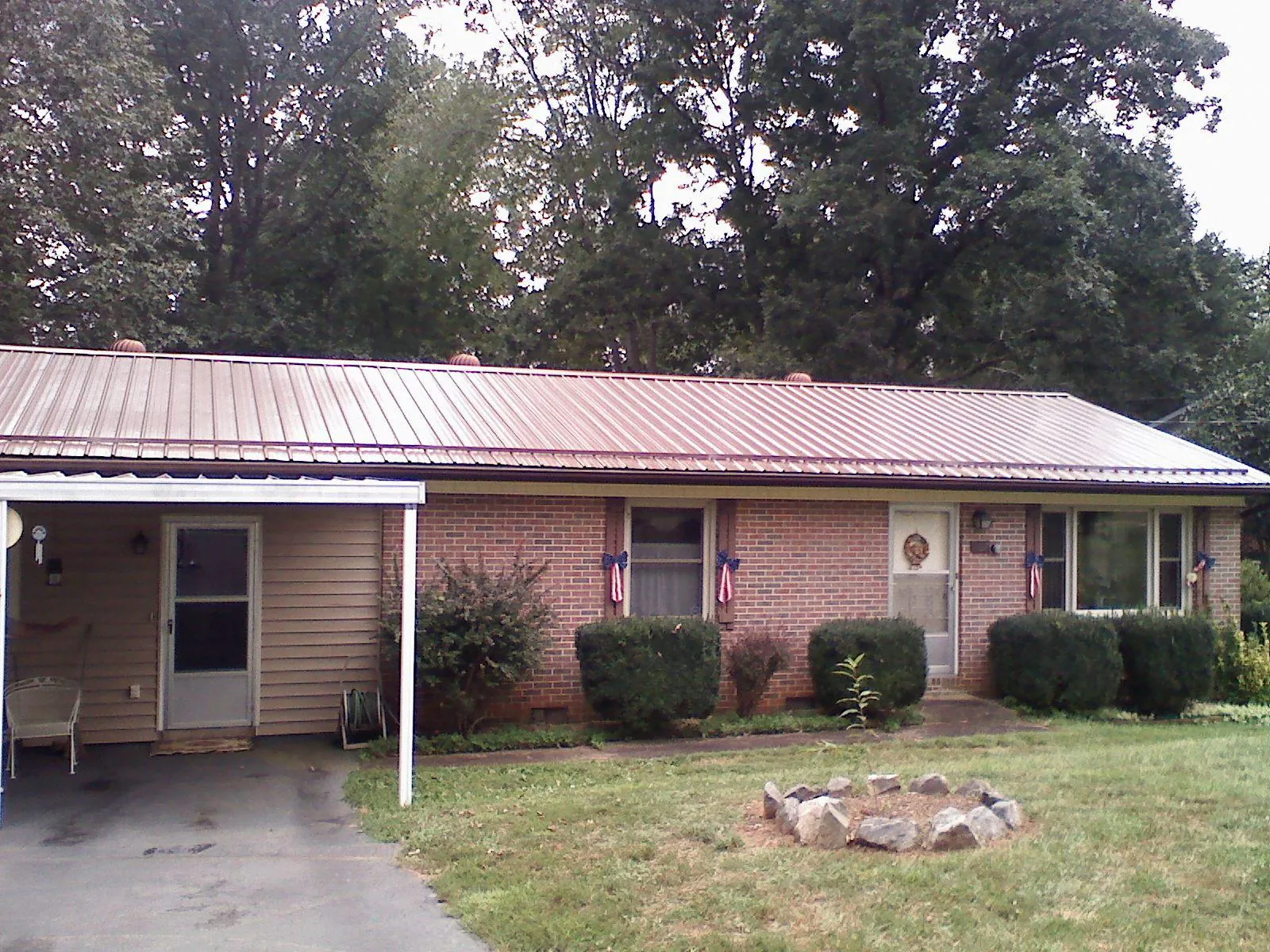 Bronze metal roof and carport on a brick ranch home — Roof Repair work by our crew in Colo